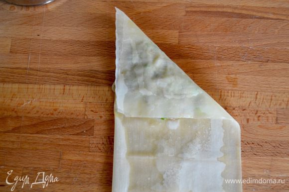 Заверните начинку в тесто, завернув в низ верхний правый угол, сложив в виде треугольника (как на фото).