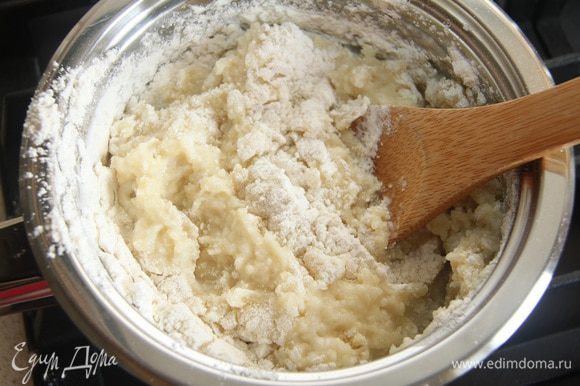 Постепенно добавить муку, энергично вмешивая ее в молочную жидкость. Выключить огонь, продолжить вымешивать тесто, пока оно не станет гладким.