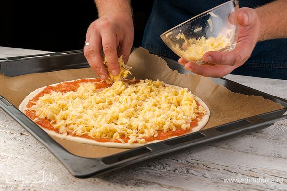 Потом посыпаем тертым сыром, сверху кладем нарезанную тонко колбасу, лук и перец. Отправляем пиццу в разогретую до 200°С духовку на 15 — 20 минут.