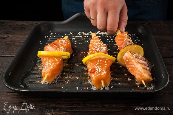 Лимон нарежьте тонкими кружочками. Нанизываем в таком порядке: кусочек лимона, затем рыбу и опять кусочек лимона. Обсыпаем рыбу кунжутными семечками. Жарим на сковороде-гриль 4–5 минут.