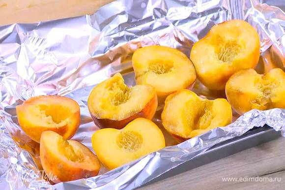 Небольшой противень выстелить пищевой фольгой, выложить персики, срезами вверх, посыпать сахарной пудрой и отправить на 2 минуты под разогретый гриль.