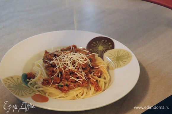Приступаем к формированию отдельных порций. На дно тарелки кладем желаемое количество спагетти. Сверху выкладываем соус и посыпаем мелко натертым твердым сыром.