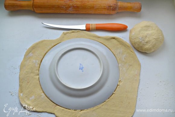 Тесто вынуть из холодильника, раскатать на пергаментной бумаге, слегка смазанной растительным маслом, и вырезать с помощью тарелки круг.