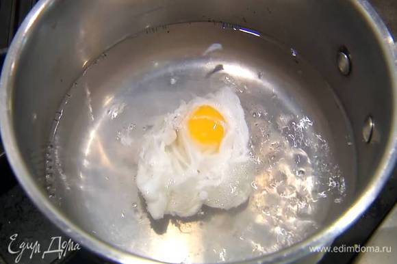 Приготовить яйцо пашот: в небольшой кастрюле вскипятить 500 мл воды, добавить 1 ч. ложку уксуса, с помощью венчика сделать маленький водоворот и в центр воронки вылить яйцо. Убавить огонь и варить 2–3 минуты, затем шумовкой выложить яйцо на бумажное полотенце. Так же приготовить второе яйцо.