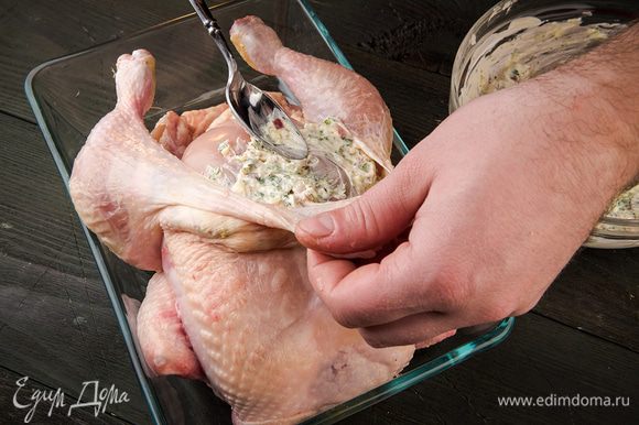 Под кожу курицы со стороны грудки, стараясь не повредить кожу, ввести половину полученной смеси. Сделать небольшие надрезы на ножках и смазать внутри полученной смесью.