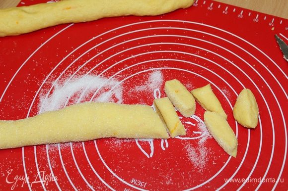Скатать 2 колбаски толщиной 4 см. Высыпать остатки сахара и обвалять в нем колбаски. Острым ножом нарезать колбаску на диски толщиной 0,7 — 1 см.