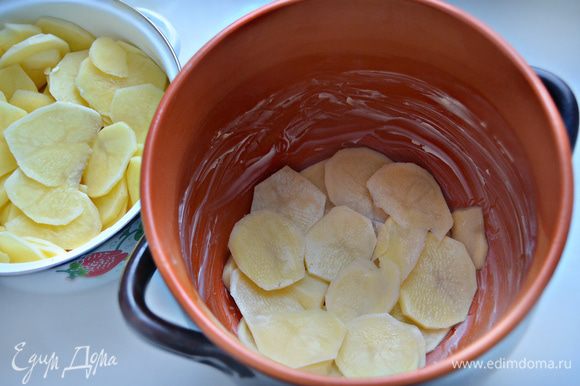 Дно и стенки керамической формы (горшочка) смажьте сливочным маслом, уложите часть картофеля.