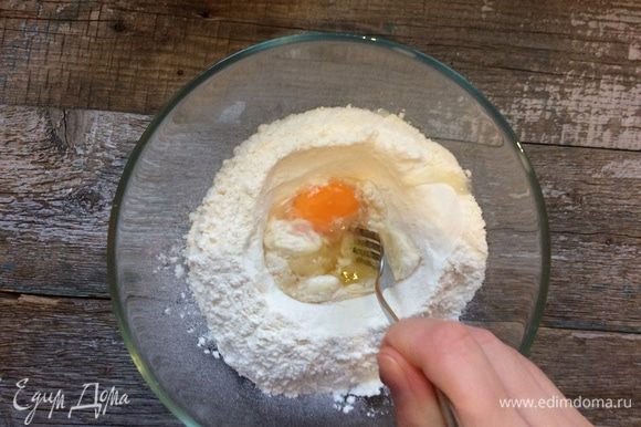 С помощью вилки начните собирать тесто так, чтобы вода и яйцо не выливались из углубления.