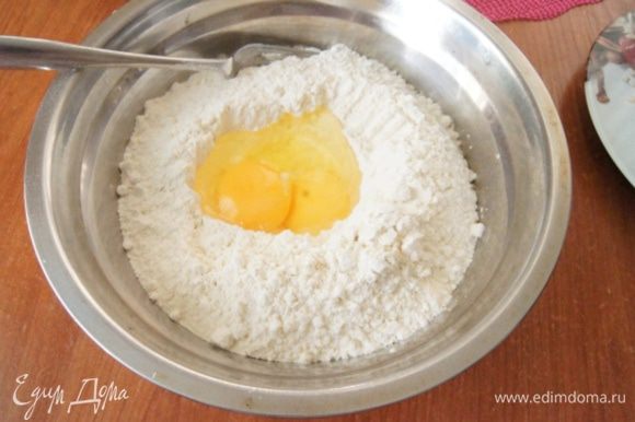 Муку просеять в миску, сделать углубление и влить желток и яйцо, немного присолить.