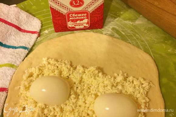 Раскатать одну часть теста. Одну половину теста посыпать сыром, сверху положить 2 половинки яйца.