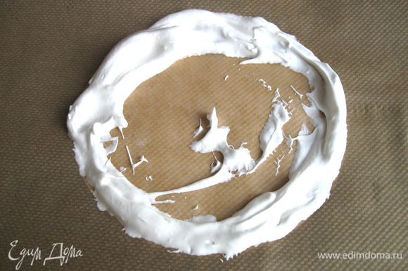 Начать выкладывать большой ложкой взбитые белки по периметру круга. Подложенную под пекарскую бумагу белую бумагу убрать.