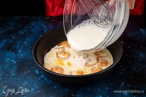 Вылейте взбитую молочно-яичную смесь к креветкам и интенсивно их перемешивайте в течение 2 минут, пока омлет не загустеет.