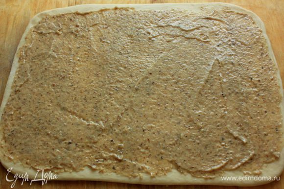 Подошедшее тесто выложить на присыпанную мукой поверхность и раскатать в прямоугольник 40 х 30 см. С помощью шпателя равномерно нанести на тесто ореховую смесь.