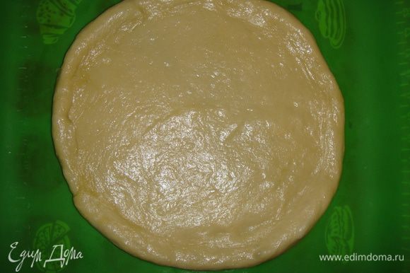Выложить тесто на силиконовый коврик (или на смазанный маслом противень) и раскатать в форме круга, делая края немного толще середины.