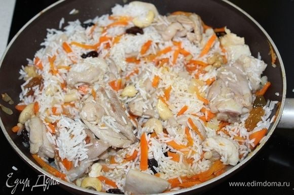 Затем добавляем рис, перемешиваем. В отдельной сухой сковороде слегка прокалить орешки и добавить к рису. Сюда же добавляем изюм.