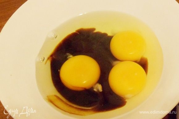 Яйца перелить в миску, добавить две столовые ложки соевого соуса.