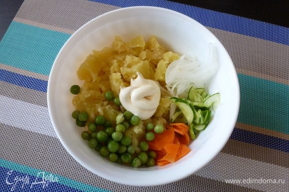 Соединим в салатнике мятый картофель, лук, огурец, морковь и зеленый горошек. Заправим майонезом.