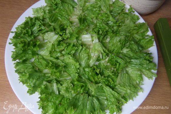 На большую плоскую тарелку нарезать или порвать салатные листья.