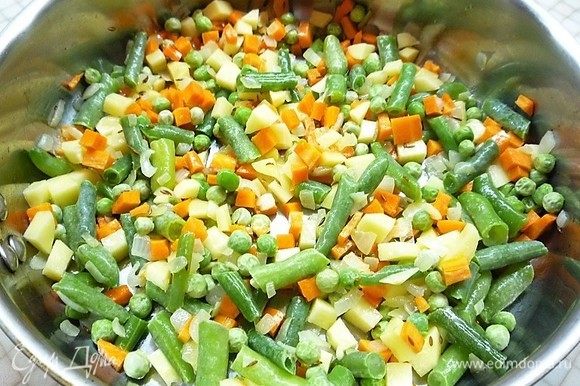 Добавляем в сковороду морковь, картофель, стручковую фасоль, горошек, перемешиваем и обжариваем овощи в течение 7 минут.