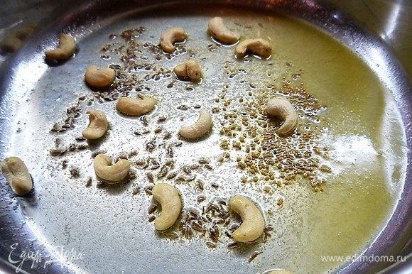 В глубокой сковороде разогреваем сливочное масло, высыпаем кумин, зерна горчицы и орешки кешью. Все перемешиваем и обжариваем в течение 1 минуты.