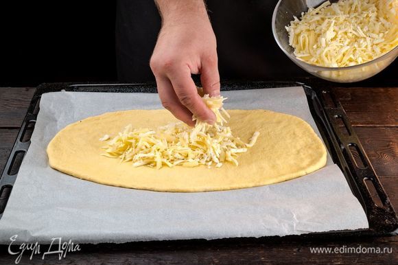 Раскатайте тесто, выложите на противень, сверху распределите сыр.