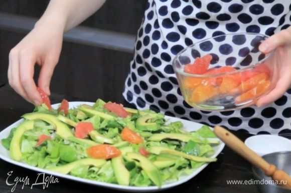 Собрать салат: выложить на блюдо подушку из салатных листьев, посыпать луком, добавить дольки авокадо и цитрусовых.