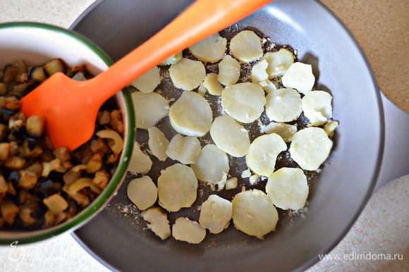 Сковороду или форму для запекания (если вы хотите запечь фриттату в духовке) смажьте растительным маслом, посыпьте сухарями, на дно разложите кружки картофеля, а затем — обжаренные с луком баклажаны.