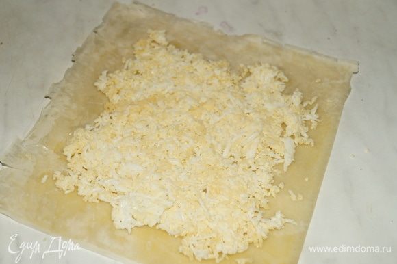 Часть яично-сырной начинки выложить на пласт теста, оставив по краям не заполненные промежутки.