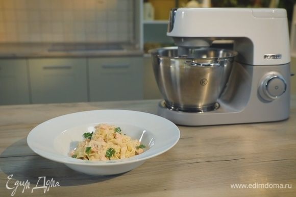 Выложите готовые тальятелле на тарелки, полейте сливочным соусом и украсьте лепестками петрушки.