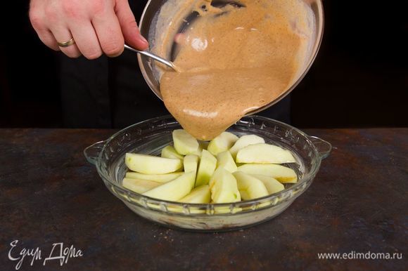 Форму для выпечки смажьте сливочным маслом. Выложите нарезанные яблоки ровным слоем и залейте равномерно тестом.