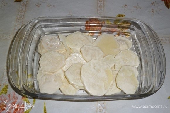 В глубокую форму для запекания выкладываем половину картофеля с майонезом. Равномерно распределяем в форме.