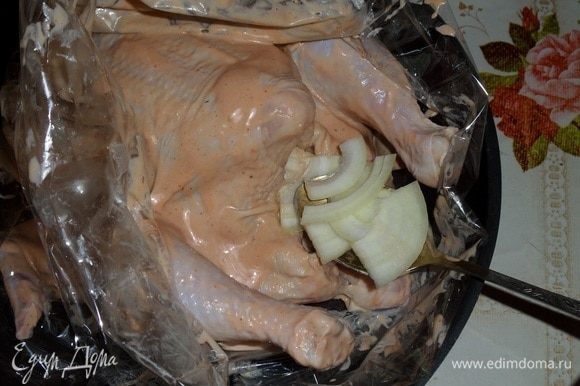 Через 1 час курицу кладем в пакет для запекания. Внутрь тушки кладем нарезанный лук и 2 ст. л. маринада.