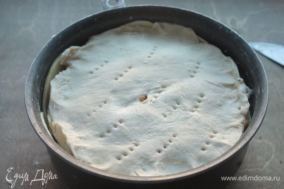 Поверх него укладываем слоеное тесто, вырезанное по форме основания пирога, и протыкаем его в нескольких местах.