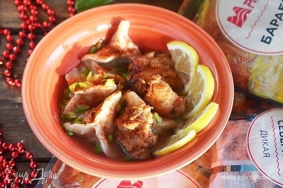 В тарелку выложите немного пельменей, сверху положите кусочек жареного рыбного филе. Подайте с ломтиками лимона и посыпьте молотым чили и зеленым луком.
