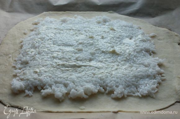 На тесто, отступая от краев примерно по 5 см, выложите рис и смажьте его тонким слоем мягкого сливочного масла.
