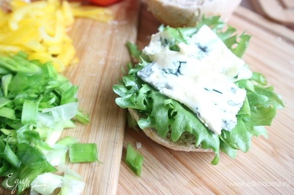 На нижнюю часть булки положить немного соуса, листики салата. Затем сыр с голубой плесенью.