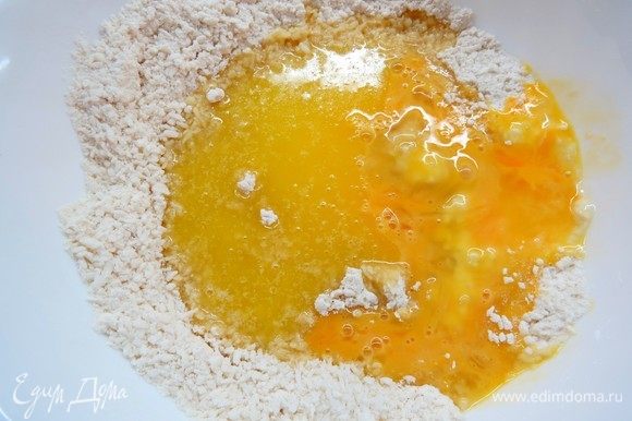 В сухие ингредиенты добавить растопленное сливочное масло и яйцо, хорошо перемешать. Должно получиться рассыпчатое песочное тесто.