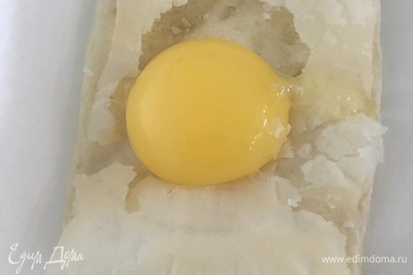 Достать из духовки полуготовые квадраты. Вырезать середину и вылить яйцо. Поставить в духовку на 5-7 минут, до зарумянивания.