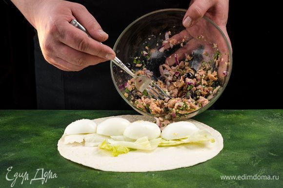 Собираем роллы. Расстелите лаваш, выложите на него салатные листья. Сверху положите несколько ложек салата и дольки яиц.