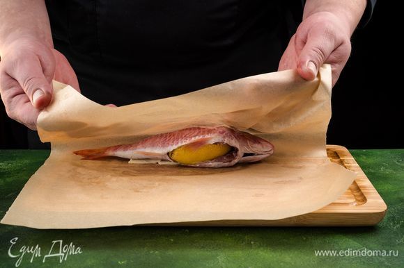 Пергамент смажьте сливочным маслом и заверните в него плотно рыбу. Запекайте 25 минут при 150°С.