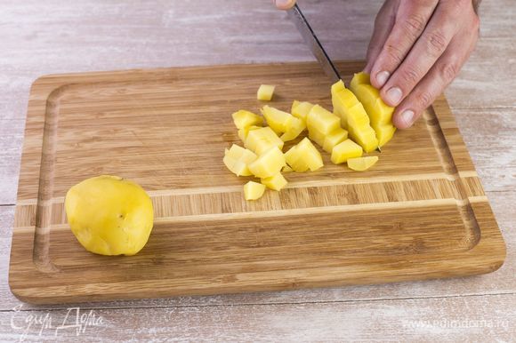 Сварите картофель в мундире, очистите от кожуры и нарежьте мелким кубиком.