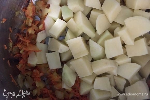 Как только лук стал прозрачным, а морковь мягче, добавляем в кастрюлю картофель, нарезанный кубиками. Перемешиваем, пару минут держим на огне и заливаем бульоном или бутилированной водой. Варить около 15 минут.