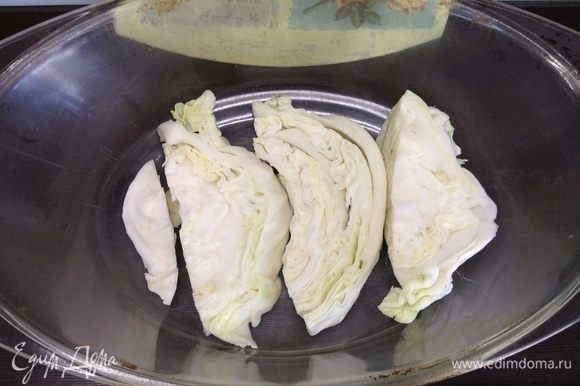 На дно глубокой посуды (у меня стеклянная с крышкой) толстенькими кусками укладываем капусту — подушка для «приема» лишнего жирка во время запекания и воздушная прослойка.