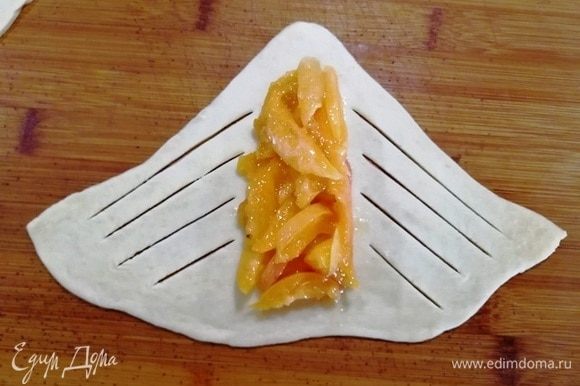 По центру треугольника выкладываем абрикосовую начинку, надрезаем тесто, как показано на фото.