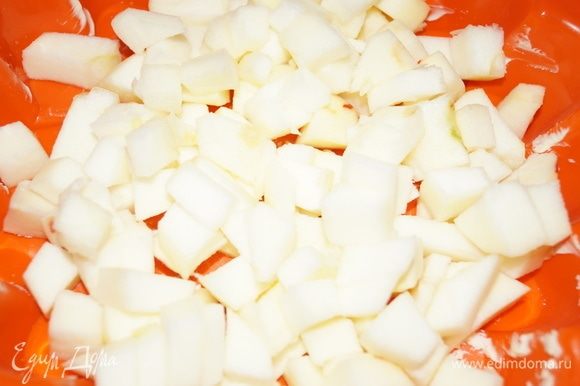 Смажьте форму маслом, на дно выложите очищенные и нарезанные на кубики яблоки.