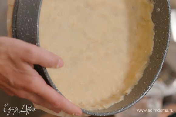 Дно разъемной формы выстелить бумагой для выпечки, смазать бумагу и стенки формы оставшимся сливочным маслом и тонким слоем выложить тесто, сформировав бортики.