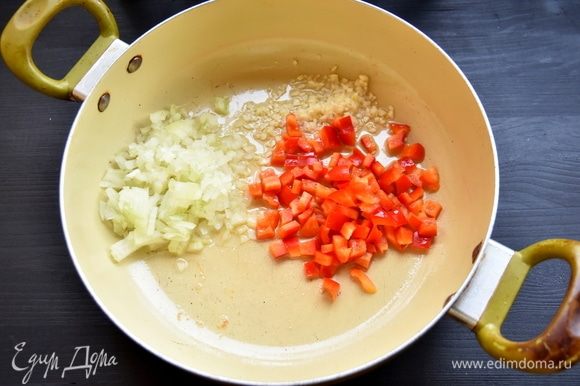 В сковороду добавьте еще 2 ст. л. оливкового масла и обжарьте нарезанные лук, чеснок и болгарский перец.