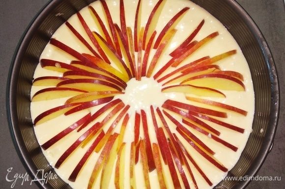 Выливаем тесто в смазанную маслом форму для выпекания (моя форма 26 см). И вставляем «ребрышком» нарезанные яблоки по кругу, начиная от края формы и оканчивая серединой.