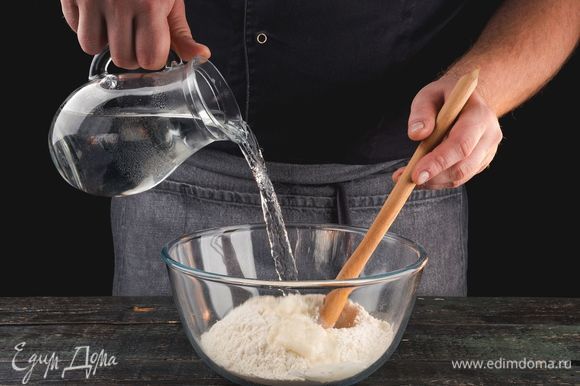 В большую миску просейте муку, добавьте стакан кипятка и соль.