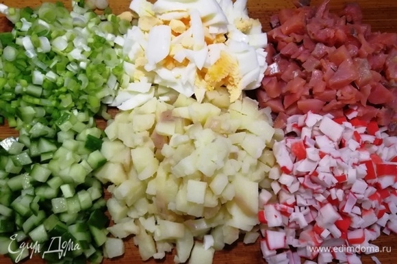 Для салата возьмем отварной картофель среднего размера, яйца некрупные (С1), крабовые палочки, огурчик средний (без сердцевины), белую часть зеленого лука, слабосоленый лосось. Все ингредиенты нарежем одинаковым кубиком.